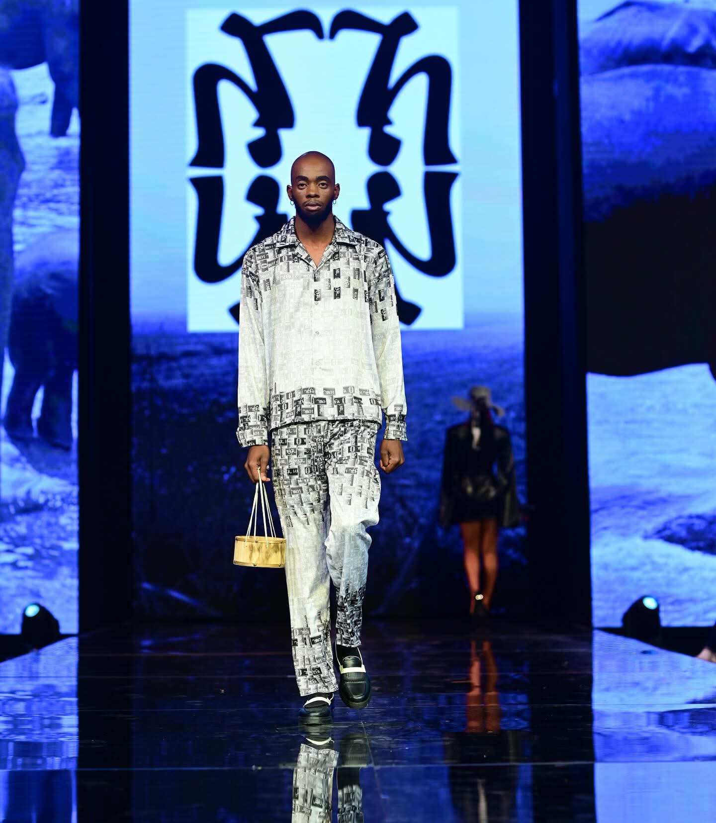 Model walking the runway in a patterned VYAGOR LOUVRE ensemble